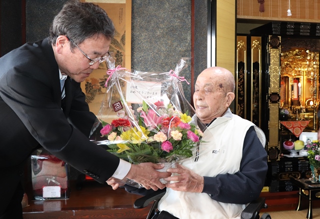 福島健康福祉部長から花かごを受け取る乙吉さん