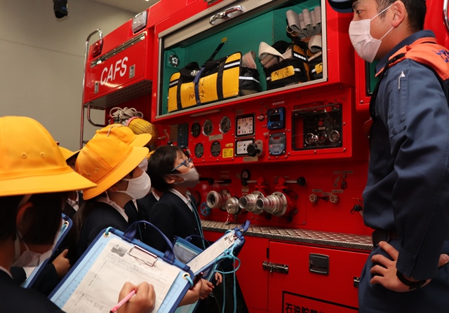 消防車両の説明をする消防職員と説明を聞く児童
