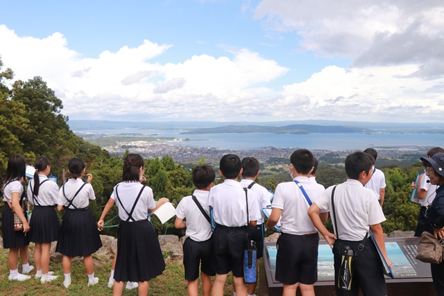 本丸跡から市街地を眺める児童たち