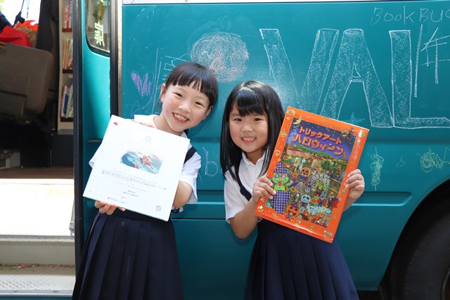 本をプレゼントされて笑顔を見せる児童たち