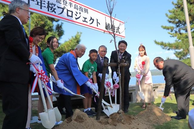 桜の木にスコップで土をかぶせる一同