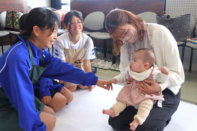 赤ちゃんとのふれあいを楽しむ児童