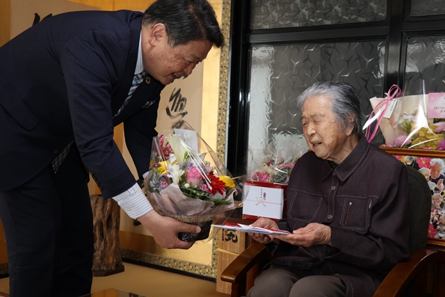市長からお祝いを受け取る君子さん